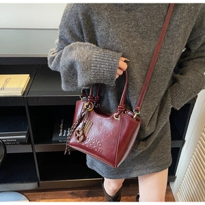 Close-up of burgundy retro bucket bag with embossed logo and golden ring hardware