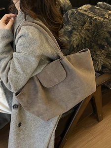 Large taupe faux suede tote bag shown on shoulder in a minimalist lifestyle setting