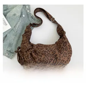 Close-up of leopard print crescent bag featuring drawstring details and adjustable strap