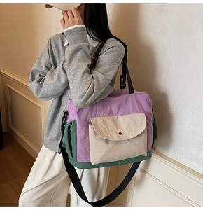 Detail of color-block tote bag showing purple and green contrast with adjustable strap