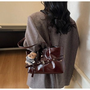 Vue détaillée du sac cabas en cuir marron brillant avec boucle et breloque ours en peluche