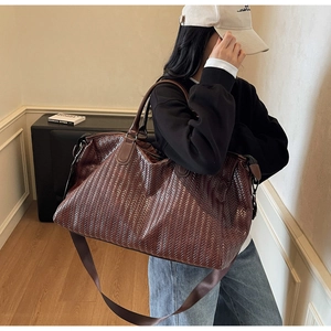 Close-up of a large dark brown woven travel bag with high-quality faux leather texture