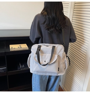 Side view of large light grey crossbody bag with adjustable wide strap and front flap pocket