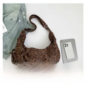 Detailed view of leopard print crossbody bag with drawstring design and denim jacket