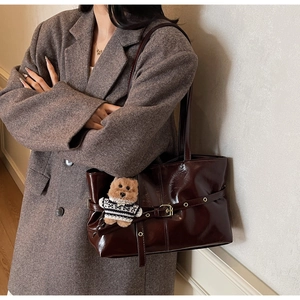 Sac cabas en cuir marron foncé avec ours en peluche porté par mannequin en costume gris