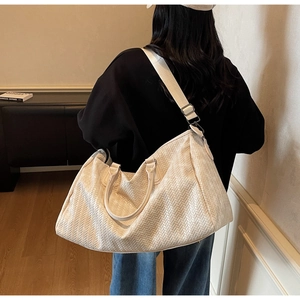 Detail of woven texture handbag with adjustable shoulder strap and cylinder handles