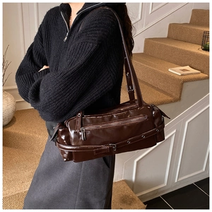 Detailed close-up of dark brown glossy bowling bag featuring stylish metal buckle accents
