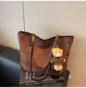 Detailed view of the embossed vintage bear pattern and suede texture of the brown tote bag