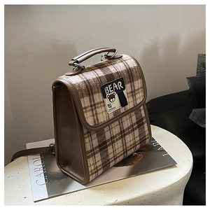 Détail du sac à main vintage à carreaux marron avec un écusson ours sur le rabat