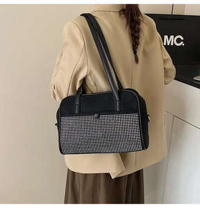 Detail of black shoulder bag with silver rhinestone patchwork shown on beige suit