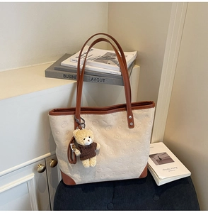Detail of cream tote bag with brown straps and embossed bear pattern on high-quality fabric