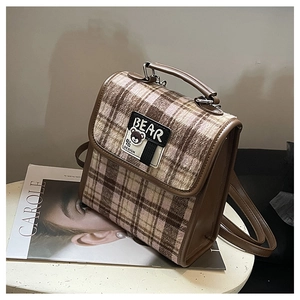 Détail d'un sac à dos en tweed à carreaux marron et rose avec patch ours et poignée