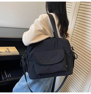 Detail of black large capacity nylon crossbody bag with wide strap and multi-pocket design
