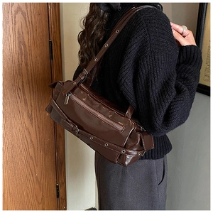 Detail of dark brown glossy leather shoulder bag with metallic eyelets and vintage buckle