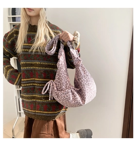 Detail of pink leopard print drawstring hobo bag shown with a retro knit sweater