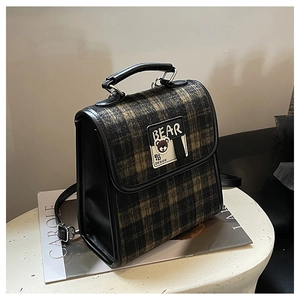 Détail d'un sac à dos vintage en laine à carreaux avec lanières en cuir et patch