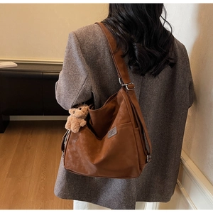 Detailed view of brown matte PU leather hobo bag with wide strap and plush bear charm