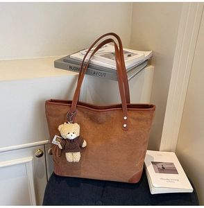 Detail of warm brown tote bag with embossed teddy bear patterns and plush bear charm