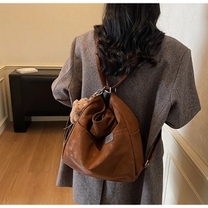 Detail of dark brown vintage backpack with soft leather texture and plush bear pendant