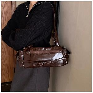 Detail of dark brown glossy patent leather shoulder bag with zipper and buckle details
