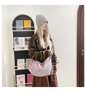 Detail of pink leopard print dumpling bag with wide crossbody strap in casual home setting
