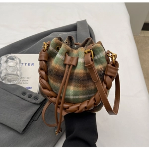 Détail du sac seau en laine avec motif à carreaux vintage et poignée en cuir tressé
