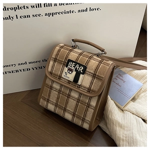 Détail du sac à carreaux vintage avec bordure en cuir marron et écusson d'ours