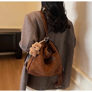 Close-up of vintage brown shoulder bag with metal chain and plush bear charm detail