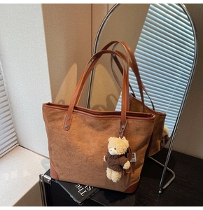 Detail of vintage brown tote bag with embossed bear patterns and plush bear charm