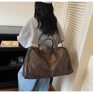 Détails de la texture cuir marron foncé et des poignées sur le grand sac fourre-tout