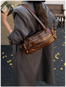 Detailed view of deep brown vintage shoulder bag with multiple zippers and utility pockets