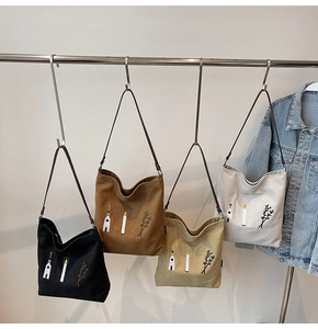 Detail of four embroidered canvas tote bags in black, brown, khaki and beige colors