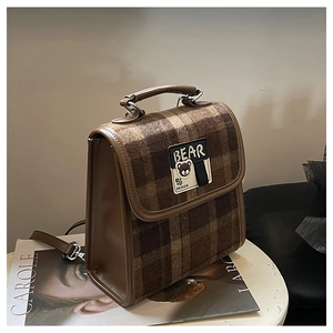 Détail du sac à dos vintage à carreaux marron avec écusson ours et poignée en cuir