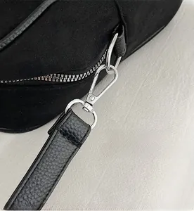 Close-up of durable silver D-ring hardware and spring hook on black leather shoulder strap