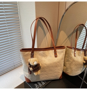 Detail of canvas tote bag with embossed bear patterns and cute plush bear charm