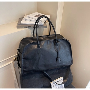 Détail du sac de voyage Boston noir à texture plissée brillante sur un siège chic