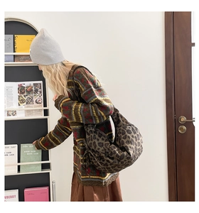 Detail of vintage leopard print crossbody bag styled with a colorful striped knit sweater