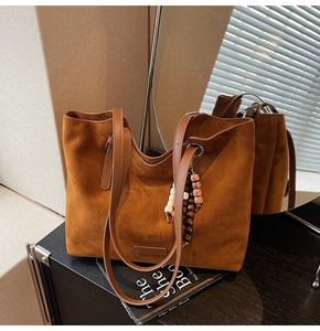 Détail du sac cabas en daim caramel avec breloque perlée rétro et écusson de marque