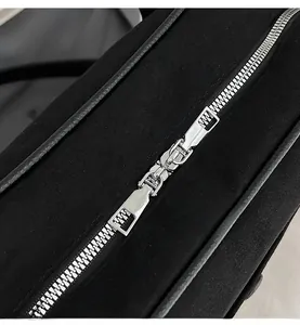 Macro shot of smooth silver zipper hardware on a black suede shoulder bag detail