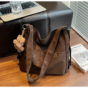 Detail of vintage brown tote bag featuring front dual pockets and cute plush bear charm