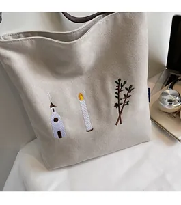 Detail of vintage beige canvas tote bag with floral embroidery and brown leather handle