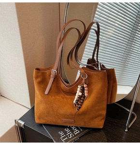 Détail du cabas en daim caramel avec pendentif en perles de bois et boucle argentée réglable