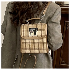 Gros plan du sac bandoulière en laine à carreaux marron avec broderie ours et cuir