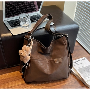 Detail of vintage brown tote bag with twin front pockets and cute plush bear charm