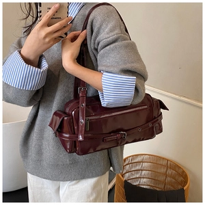 Detail of burgundy patent leather shoulder bag featuring retro buckles and zippers