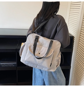 Detail of light grey nylon tote bag showing front flap pocket and large capacity