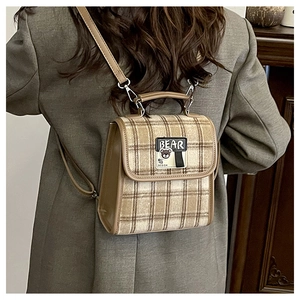 Détail d'un mini sac à dos à carreaux vintage avec écusson ours porté sur un blazer