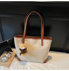Detail of vintage canvas tote bag with bear pattern, leather trim and bear charm