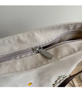 Detail of vintage canvas bag showing silver zipper and floral embroidery motifs