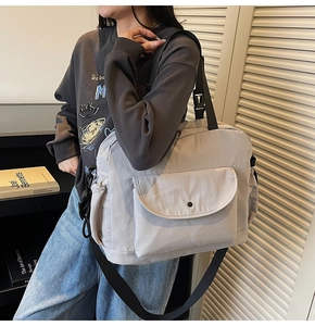 Detail of grey minimalist nylon tote bag with wide black strap and front flap pocket